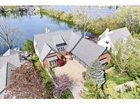 Gorgeous aerial view of a red brick home with a well manicured yard along a lake at 3748 Bay Rd S Dr, Indianapolis, IN 46240