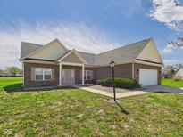 Charming brick home with an attached garage, lovely landscaping, and a well-manicured lawn on a beautiful day at 6606 Colt Ln, Anderson, IN 46013