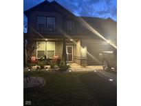 Charming two-story home with a well-manicured lawn, covered porch, and a cozy seating area at twilight at 912 Grassy Branch Dr, Indianapolis, IN 46239