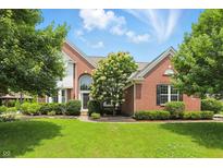 Charming two-story brick home with a manicured lawn and mature trees, creating a welcoming curb appeal at 9318 Windrift Way, Zionsville, IN 46077