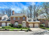 Charming brick townhome featuring attached garages, manicured landscaping, and classic architectural details at 13587 Kensington Pl, Carmel, IN 46032