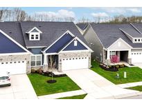 Beautiful home with stone accents, a blue exterior, attached garage, and well-maintained landscaping at 17066 Cole Evans Dr, Noblesville, IN 46060