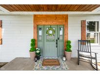 Charming front door with wooden trim, wreath, potted plants, and welcome mat at 4622 W 400 S, Trafalgar, IN 46181