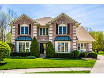 Charming two-story brick home with manicured lawn and lush greenery on a sunny day at 4731 Moss Creek Ct, Indianapolis, IN 46237