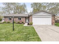 Charming brick home featuring an attached garage, manicured lawn, and inviting front entrance at 7656 Madden Ln, Fishers, IN 46038