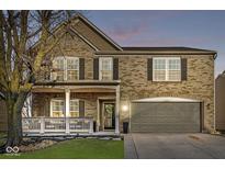 Charming two-story brick home with attached garage, covered porch, and manicured front lawn at 8327 Andrusia Ln, Indianapolis, IN 46237