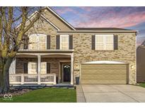 Inviting two-story brick home featuring a charming front porch and well-maintained landscaping at 8327 Andrusia Ln, Indianapolis, IN 46237