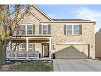 Inviting two-story brick home featuring a charming front porch and an attached two-car garage at 8327 Andrusia Ln, Indianapolis, IN 46237