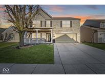 Charming two-story home with a covered porch, well-manicured lawn, and attached two-car garage at 8327 Andrusia Ln, Indianapolis, IN 46237