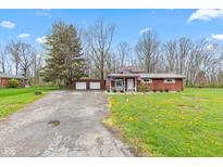 Charming single-story home with a cozy front porch, American flags, and a detached two-car garage at 874 S Sycamore Dr, Greenfield, IN 46140
