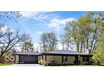 Charming ranch home featuring a stone facade, attached garage and inviting landscaping at 9944 Holaday Dr, Carmel, IN 46032