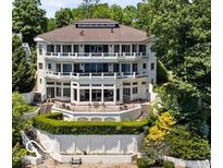 Multi-level waterfront home with multiple balconies and outdoor seating area surrounded by mature trees at 10919 Brigantine Dr, Indianapolis, IN 46256