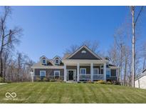 Charming two-story home with a welcoming front porch and well-maintained lawn on a sunny day at 13705 Beam Ridge Dr, McCordsville, IN 46055