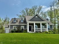 Charming home featuring a covered front porch with white columns, dormer windows and manicured lawn at 13705 Beam Ridge Dr, McCordsville, IN 46055