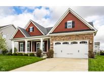 Lovely home showcasing a spacious two-car garage, stone accents, and a neatly kept lawn with lush green grass at 15144 Bentfield Ct, Fishers, IN 46037
