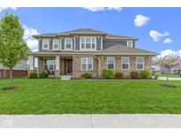 Charming two-story brick home featuring a covered front porch and manicured lawn at 1979 Lunenburg Dr, Westfield, IN 46074