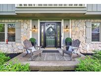Inviting front porch with stone accents, featuring seating and a wreath-adorned door with sidelights at 2011 Pin Oak Ct, Indianapolis, IN 46260