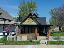 An exterior shot of a cottage-style home with yellow shingles and a picket fence at 3320 E New York St, Indianapolis, IN 46201