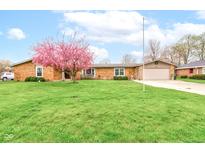 Charming brick home with a well-manicured lawn and a beautiful pink flowering tree in the front yard at 4013 Colonial Dr, Anderson, IN 46012