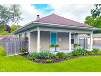 Charming home with a welcoming porch, beautiful landscaping, and a bright blue front door at 6194 Evanston Ave, Indianapolis, IN 46220
