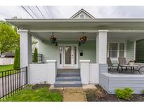 Charming home with a inviting front porch, featuring a cozy seating area and decorative hanging plants at 926 Olive St, Indianapolis, IN 46203