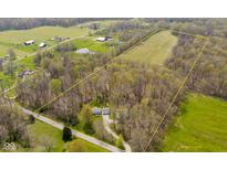 Areal view of a home in a wooded and open field setting with a pond and outbuildings in the surrounding area at 9570 S 300 W, Columbus, IN 47201