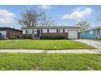 Charming single-story home featuring a brick facade, attached garage and well-maintained front lawn with mature trees at 1819 S Drexel Ave, Indianapolis, IN 46203