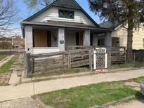 Exterior view of an older home with a ramp leading to the front porch, boarded windows, and a chain-link fence at 1924 E Maryland St, Indianapolis, IN 46201
