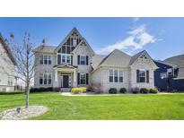 Charming two-story home with a well-manicured lawn, elegant brickwork, and striking architectural details under a bright blue sky at 3997 Spylaw Rd, Bargersville, IN 46106