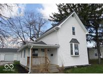 Charming two-story home with a covered porch and a classic white exterior and a detached garage at 418 N 14Th St, Elwood, IN 46036