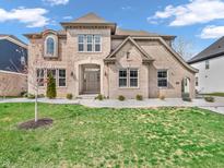 Stunning brick home featuring a manicured lawn, elegant landscaping, and a welcoming front entrance at 6044 Shallow Crk Ln, Indianapolis, IN 46237