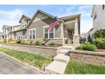 Charming home with a stone retaining wall, landscaped garden, and an American flag proudly displayed at 7092 Cherry Creek Blvd, Carmel, IN 46033