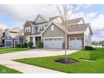 Attractive two-story house with a large driveway and a well-maintained lawn with a young tree at 15986 Bugle Ridge Dr, Noblesville, IN 46060