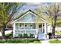 Charming bungalow featuring light blue siding, a cozy front porch, and beautifully landscaped yard at 316 S Arlington Ave, Indianapolis, IN 46219