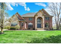 Two-story brick home boasts stone accents, arched entryway, a well-manicured lawn, and professional landscaping at 3940 Woodcrest Ct, Westfield, IN 46062