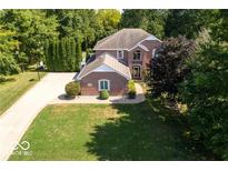 Aerial view of a beautiful brick home with lush landscaping and a circular driveway at 5773 Station Hill Dr, Avon, IN 46123