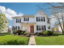 Charming two-story white home with a red door, American flag, and well-maintained landscaping at 715 Stockbridge Dr, Westfield, IN 46074