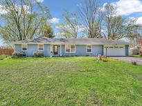Charming single-story home features a manicured front lawn, blue painted brick exterior, and an attached two-car garage at 7671 Sherry Ln, Brownsburg, IN 46112