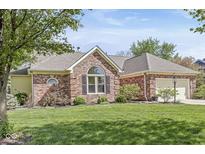 Charming brick home featuring a manicured lawn, mature landscaping, and an attached two-car garage at 768 Grace Ct, Carmel, IN 46032