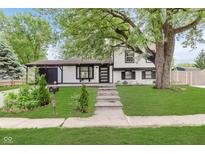 Charming home with lush green lawn, stone walkway, and mature shade tree in the front yard at 8041 Barry Rd, Indianapolis, IN 46219