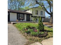 Charming two-story home with manicured lawn and a garden bed filled with flowers at 8041 Barry Rd, Indianapolis, IN 46219