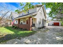 Charming two-story home features a red brick porch and a detached garage in the backyard at 207 S Arlington Ave, Indianapolis, IN 46219