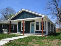 Charming home featuring a blue front door, red pillars, and well-maintained lawn at 4230 Kingsley Dr, Indianapolis, IN 46205