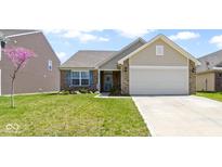 Charming home featuring a well-manicured lawn, brick accents, a two-car garage, and a delightful splash of color from a flowering tree at 2427 Apple Tree Ln, Indianapolis, IN 46229
