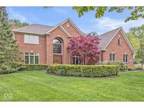 Beautiful brick home featuring a manicured lawn, mature trees, and a circular garden in the front yard at 3790 Steeplechase Dr, Carmel, IN 46032