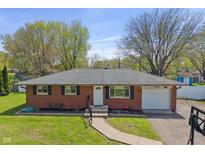 Charming brick home with an attached garage, landscaped yard, and inviting front entrance in a suburban neighborhood at 615 W Stop 11 Rd, Indianapolis, IN 46217