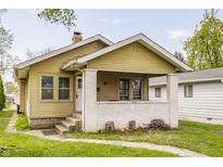 Charming bungalow with a brick porch, chimney, yellow siding, and well-maintained landscaping in a residential neighborhood at 637 Berkley Rd, Indianapolis, IN 46208