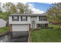 Charming split-level home featuring a well-manicured lawn, attached garage and lovely landscaping at 9034 Caminito Ct, Indianapolis, IN 46234
