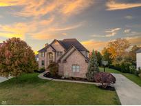 Beautiful brick home featuring an arched entryway, well-manicured lawn, long driveway, and basketball court at 12372 Ostara Ct, Fishers, IN 46037