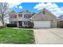 Charming two-story home with a well-manicured lawn, brick exterior and two car garage at 1611 Connemara Rd, Indianapolis, IN 46217